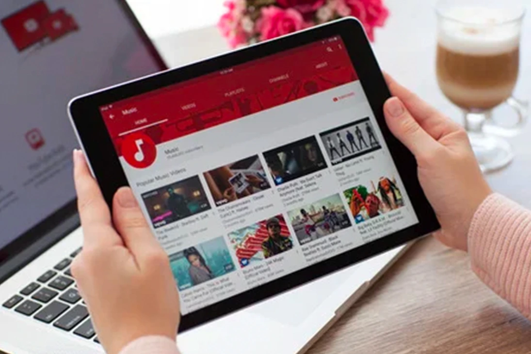 Person holding a tablet displaying a YouTube-style video browsing interface, representing video advertising and online media targeting.