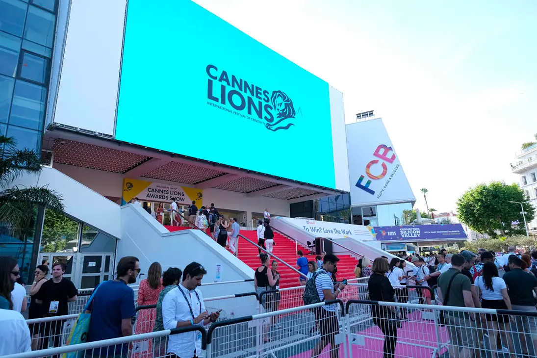 Crowd gathered outside the Cannes Lions festival venue with a large turquoise Cannes Lions sign above the entrance.