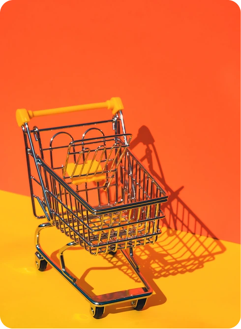 Mini shopping cart on a bright orange background, representing ecommerce marketing and online sales strategy.